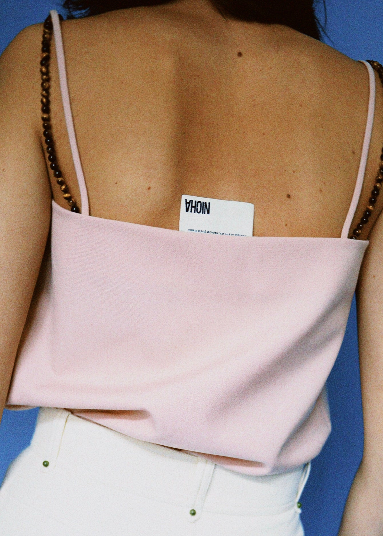 Notre haut à fines bretelles Sydney, coloris rose doux, paire de bretelles amovibles en oeil de tigre. Porté avec notre pantalon Dee Why en coton bio écru.