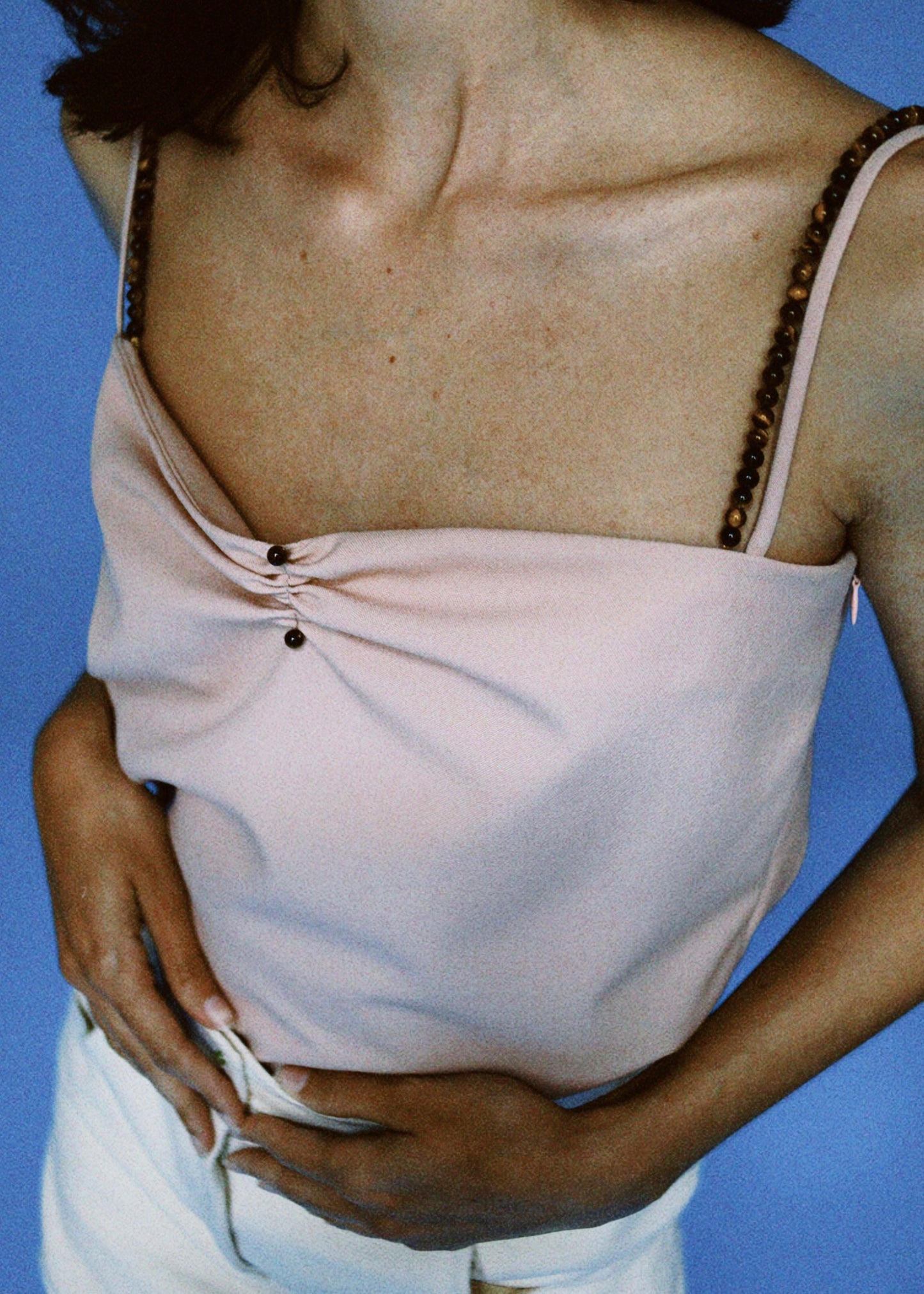 Notre haut à fines bretelles Sydney, coloris rose doux, paire de bretelles amovibles en oeil de tigre. Porté avec notre pantalon Dee Why en coton bio écru.